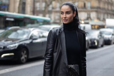 woman in black leather jacket standing on sidewalk during daytime