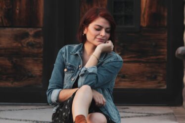 woman wearing blue denim jacet sitting on pavement